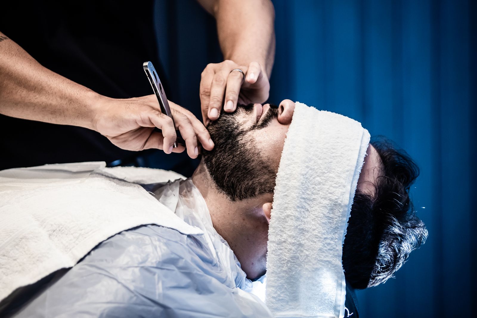 A man relaxing under a hot towel at the barber